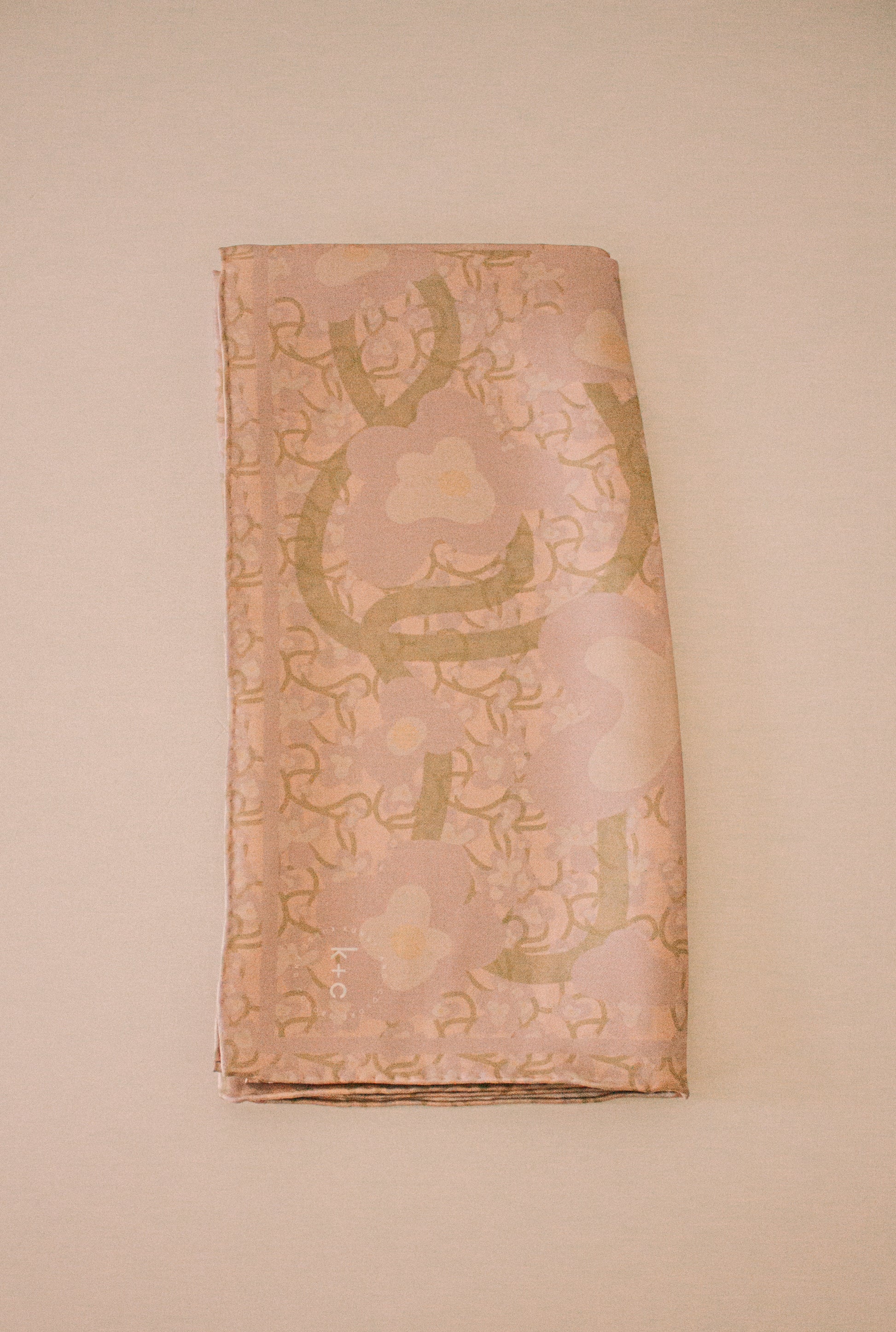 Folded silk scarf with floral patterns on a beige background