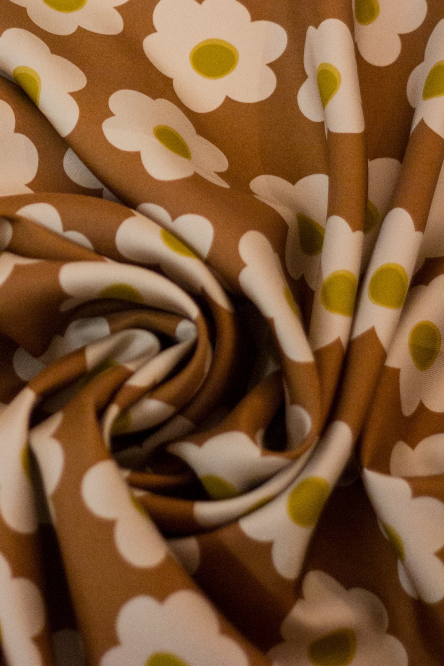 Detailed view of the 'Daisy Brown' scarf by Kunst & Colore. The print features small cream-coloured daisies arranged in a uniform square, on a brown background. 