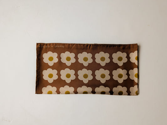 Silk scarf with white daisy pattern on a brown background, displayed against a plain background.