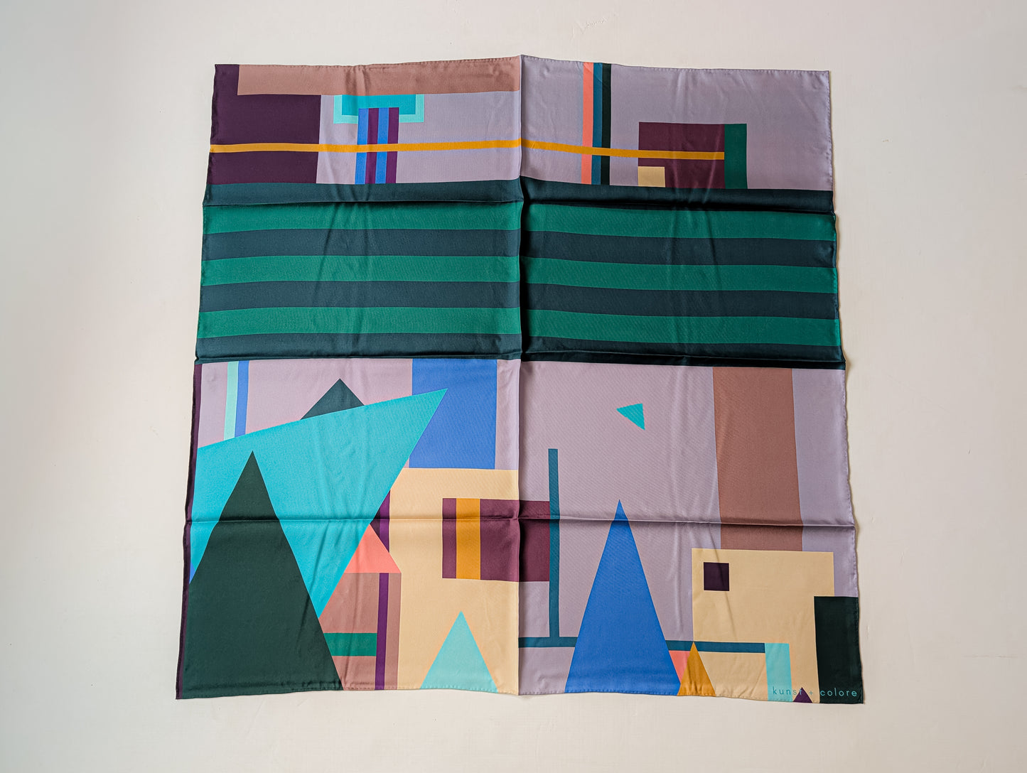 Colorful geometric-patterned silk scarf on a white background